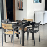 Stylish black dining table with gray and natural woven pattern chairs, perfect for modern indoor spaces.