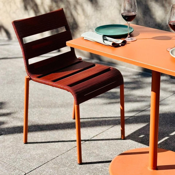 Stylish maroon slatted chair paired with a vibrant orange table, perfect for outdoor dining.
