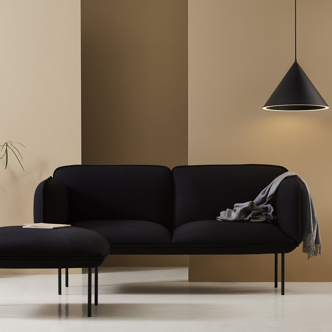 Black velvet sofa with sleek lines, set against warm beige and taupe walls, accentuated by a minimalist black pendant light.