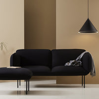 Black velvet sofa with sleek lines, set against warm beige and taupe walls, accentuated by a minimalist black pendant light.