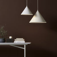 White conical pendant lamps against a rich brown wall, complementing a minimalist table setup.