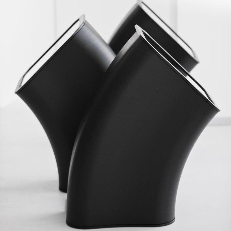 Three sleek, curved black planters with a glossy finish and white interiors, showcasing modern design and angular shapes.