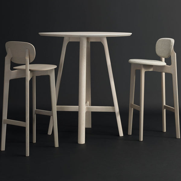 Light-colored wooden table and chairs with minimalist design, featuring smooth surfaces and clean lines against a dark background.