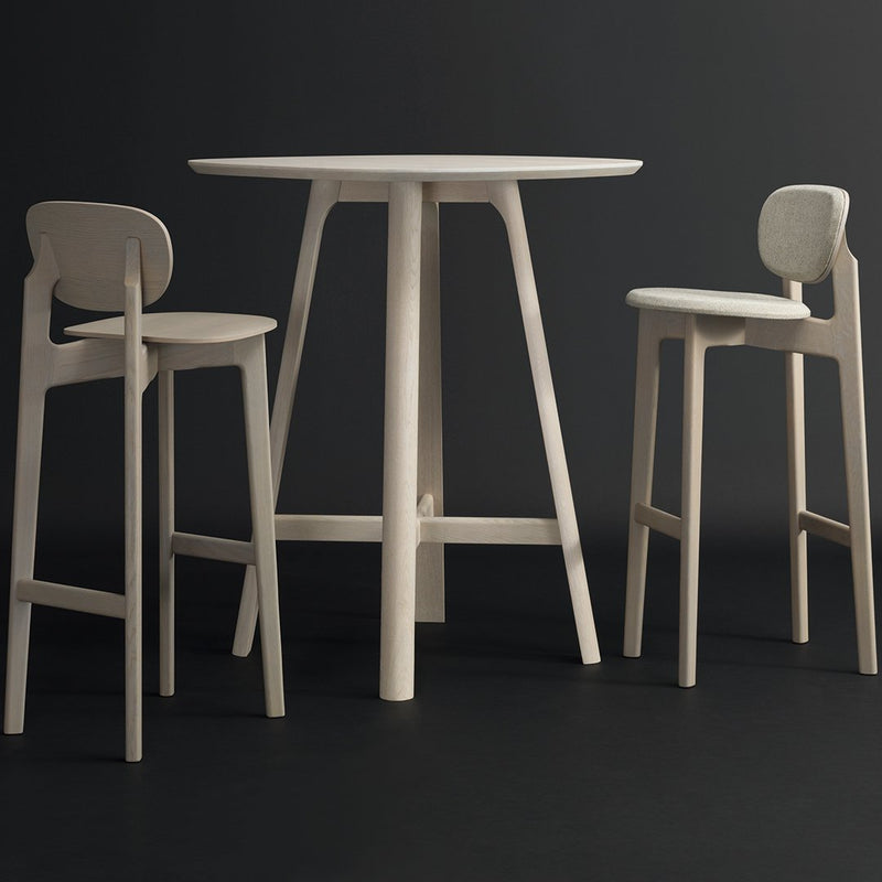 Light-colored wooden table and chairs with minimalist design, featuring smooth surfaces and clean lines against a dark background.