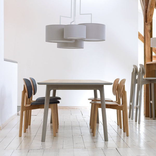 Light wood dining table with gray chairs featuring natural textures and clean lines in a modern, minimalist setting.