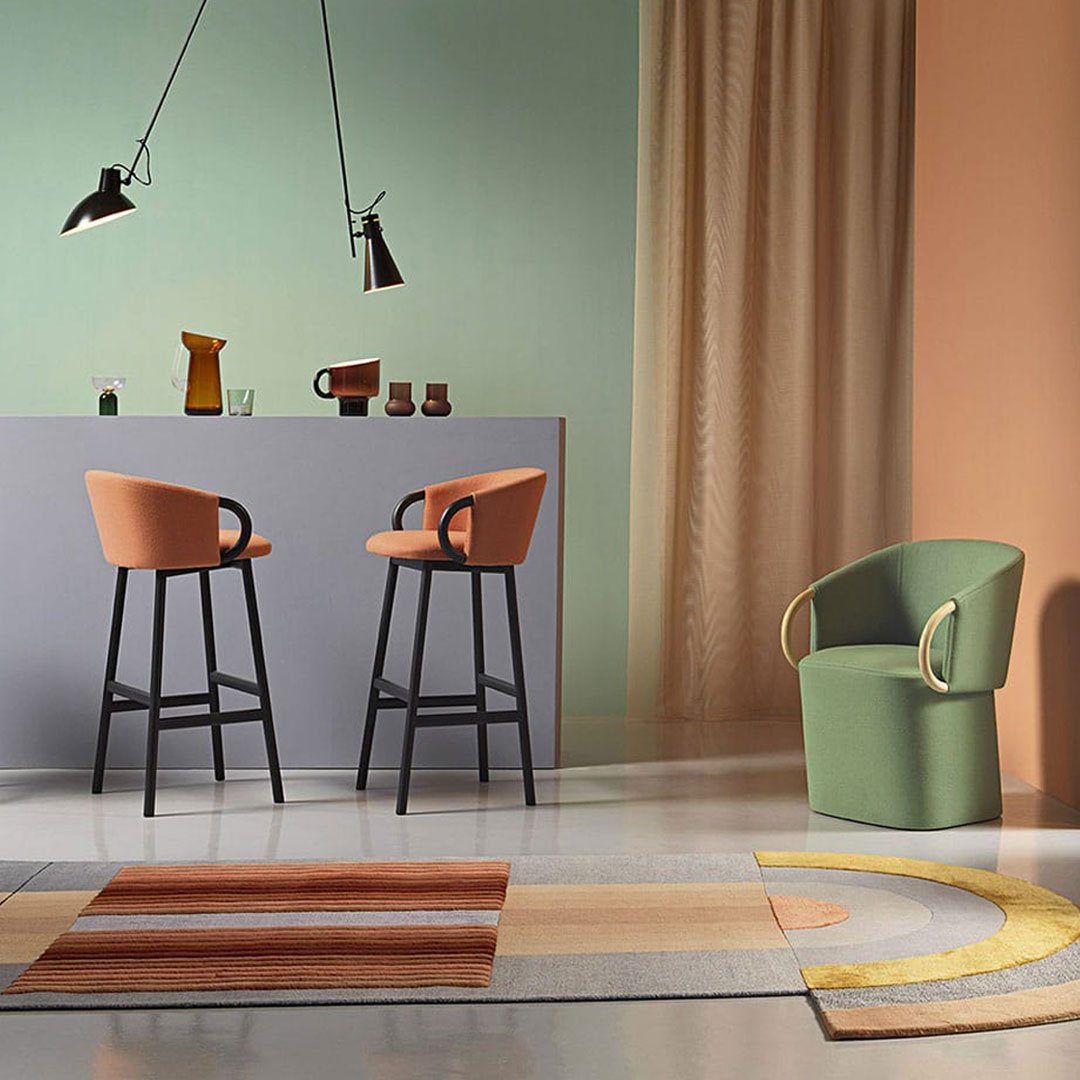 Modern chairs with orange and green accents, set against pastel walls and a patterned rug in earthy tones.