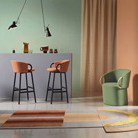 Modern chairs with orange and green accents, set against pastel walls and a patterned rug in earthy tones.