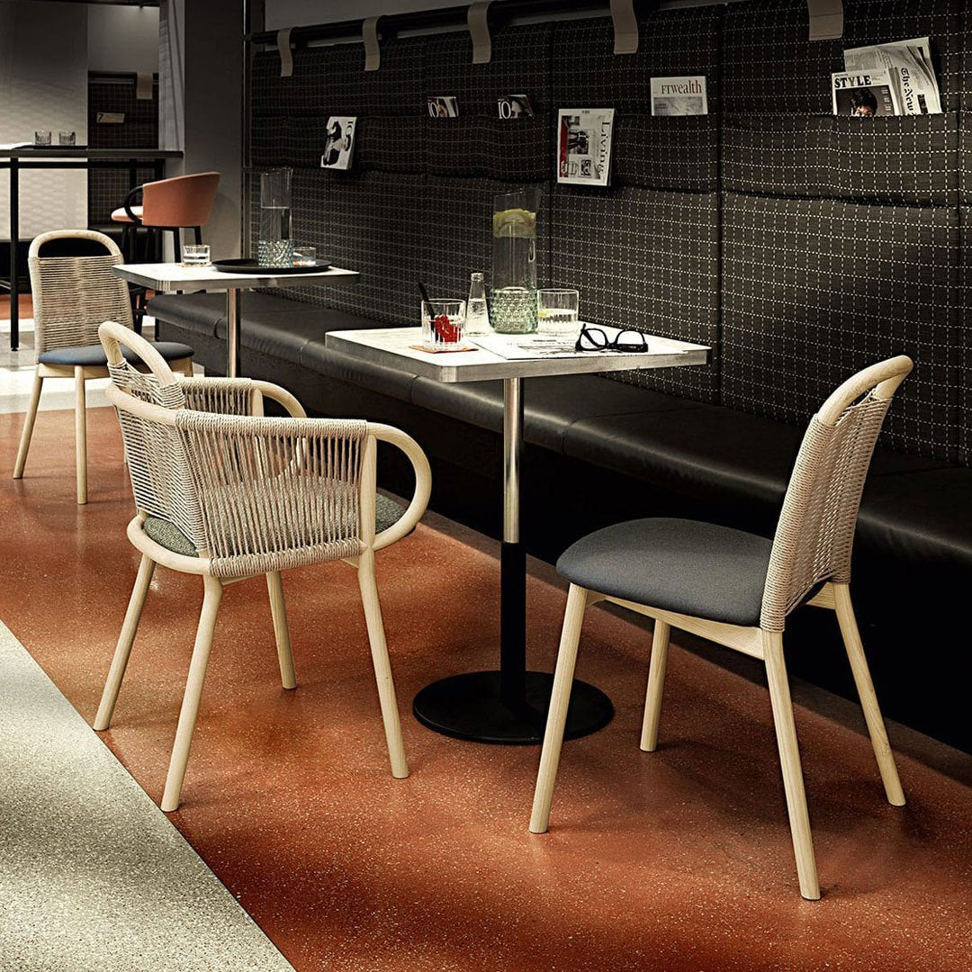 Light beige and gray chairs with woven patterns, complemented by a dark black wall and terracotta flooring.