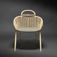 Beige rattan chair with grey patterned cushion, featuring a modern, minimalist design against a dark background.