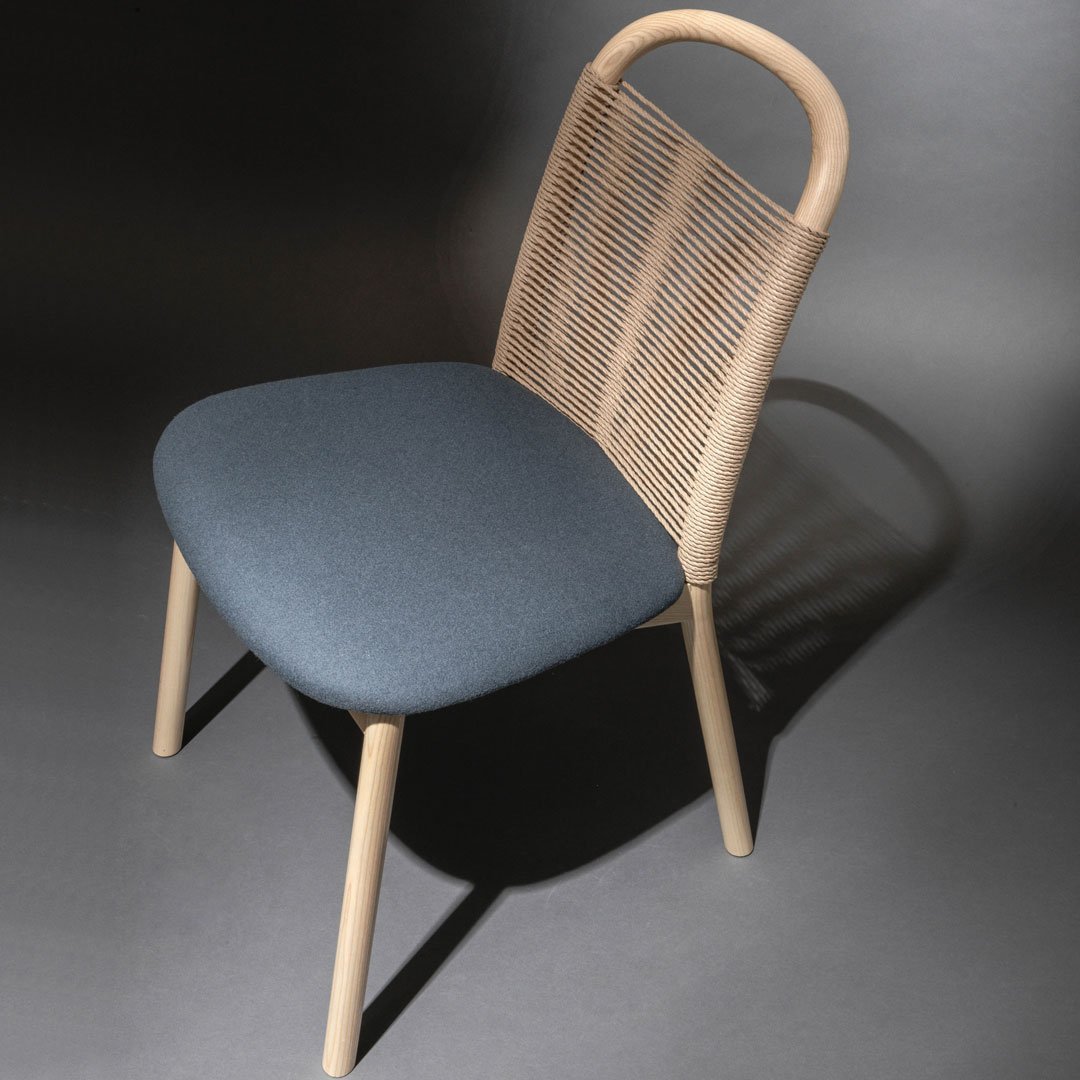 Light beige woven back chair with a solid navy blue cushion, styled for modern decor.