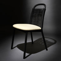 Black wicker chair with a cream cushion, featuring sleek lines and a modern design. Perfect for stylish interiors.