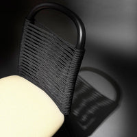 Black woven chair back with cream seat against a dark background, showcasing texture and contrast in design.