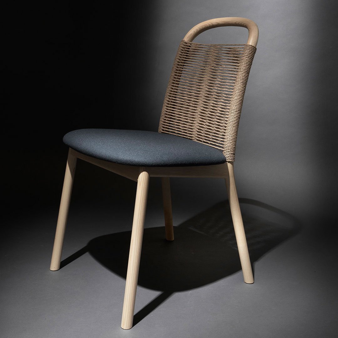 Natural beige woven chair with a dark blue padded seat, set against a dark background. Modern and stylish design.