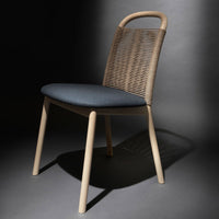 Natural beige woven chair with a dark blue padded seat, set against a dark background. Modern and stylish design.
