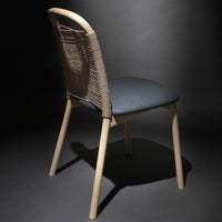 Beige chair with a woven pattern back and dark blue seat, set against a dramatic black backdrop.
