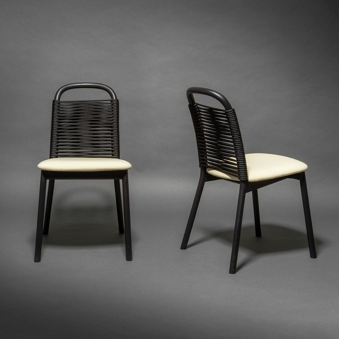 Black woven chair with cream cushion, showcasing a modern design and sleek lines against a dark background.