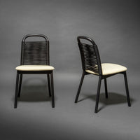 Black woven chair with cream cushion, showcasing a modern design and sleek lines against a dark background.