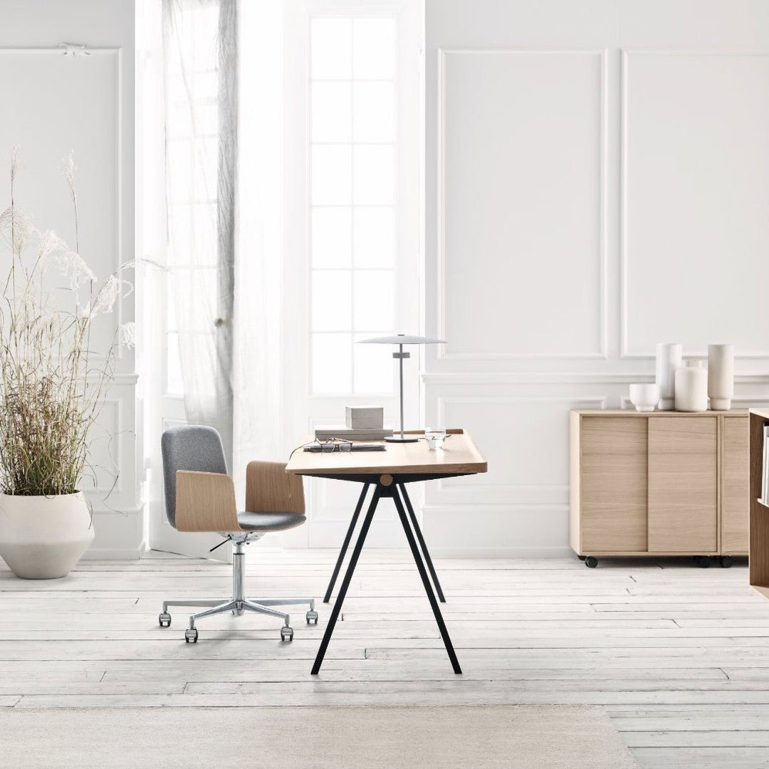 Modern wooden table with black legs, surrounded by neutral tones and soft textures in a bright, airy room.