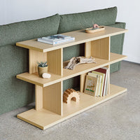 Wooden shelf with natural wood finish, vertical ribbed pattern, complemented by a soft green couch in the background.