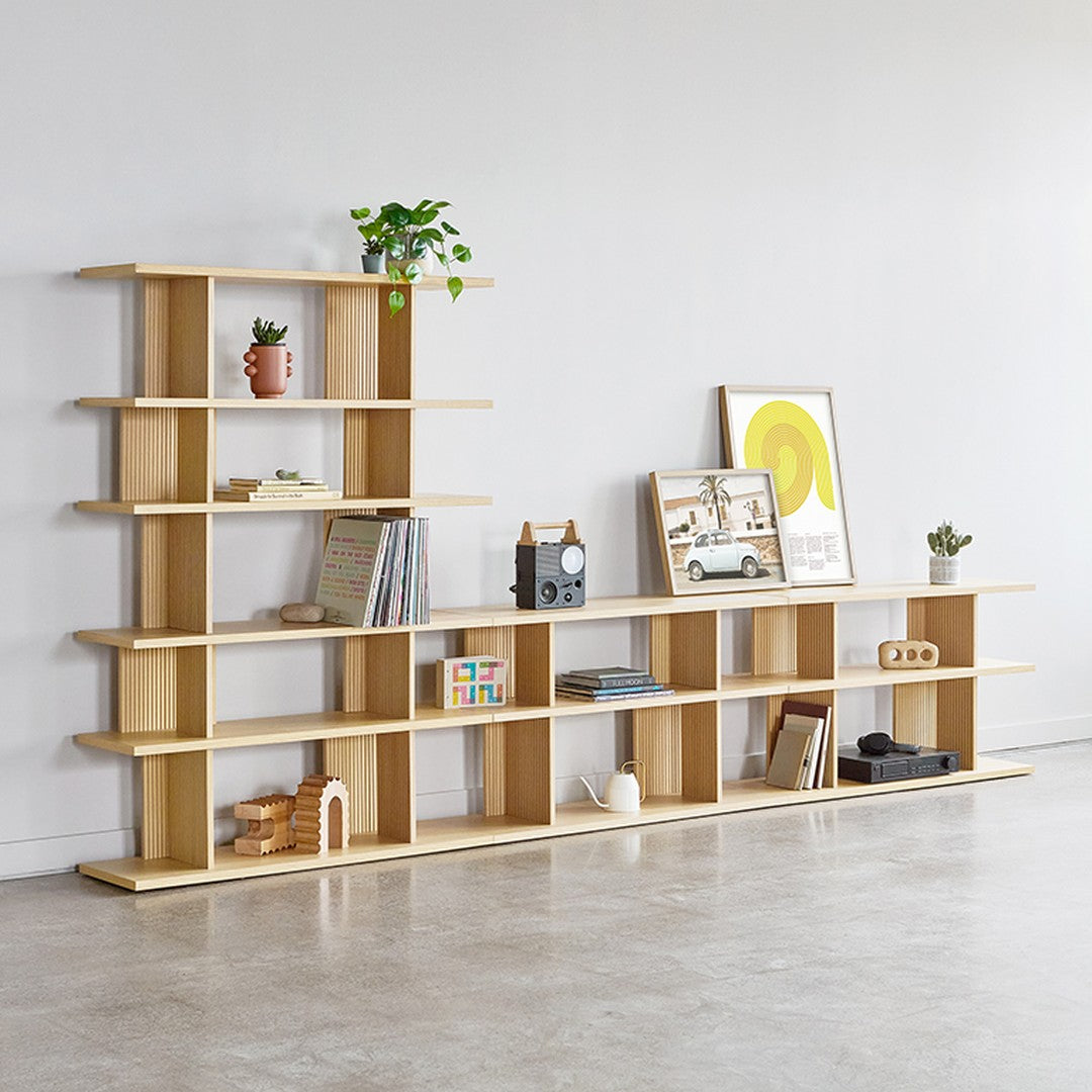 Light wood bookshelf with a modern design, featuring open shelves and a clean, minimalist pattern against a neutral backdrop.