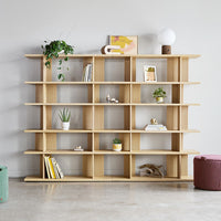 Light wood shelving unit with open compartments, featuring greenery and a pop of color from decor items.