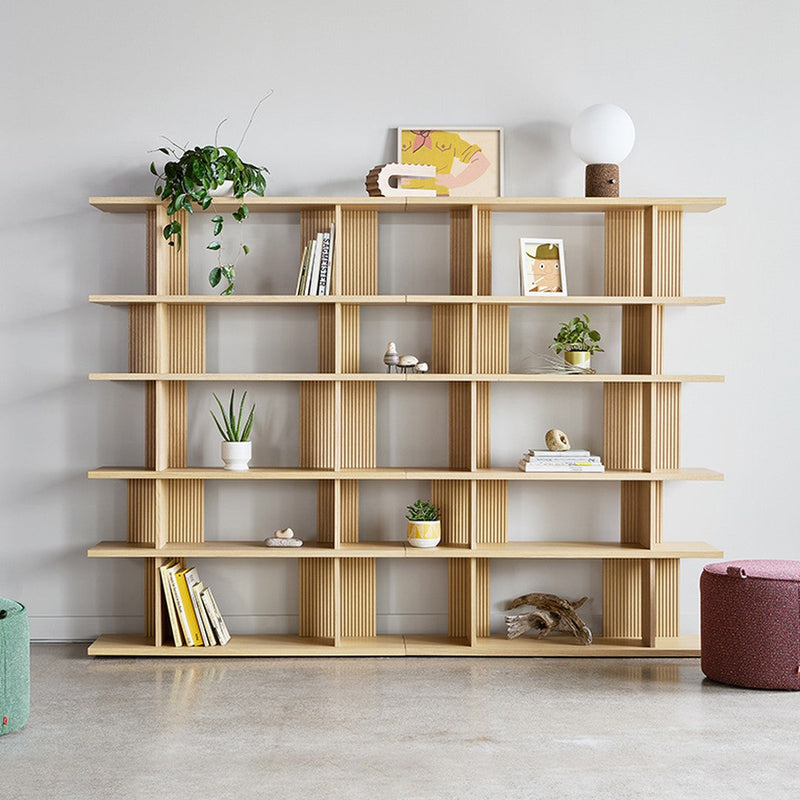 Light wood shelving unit with open compartments, featuring greenery and a pop of color from decor items.
