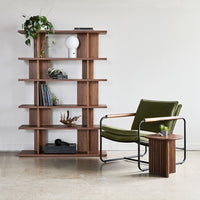 Modern wooden shelving unit with rich brown tones, paired with a sleek green chair and minimalistic accents.