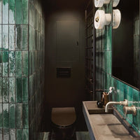 Glossy emerald green tiles with a sleek black backdrop and modern fixtures in a stylish bathroom setting.