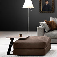 Brown plush ottoman with geometric design, paired with a grey sofa and warm-toned cushions, in a modern interior setting.