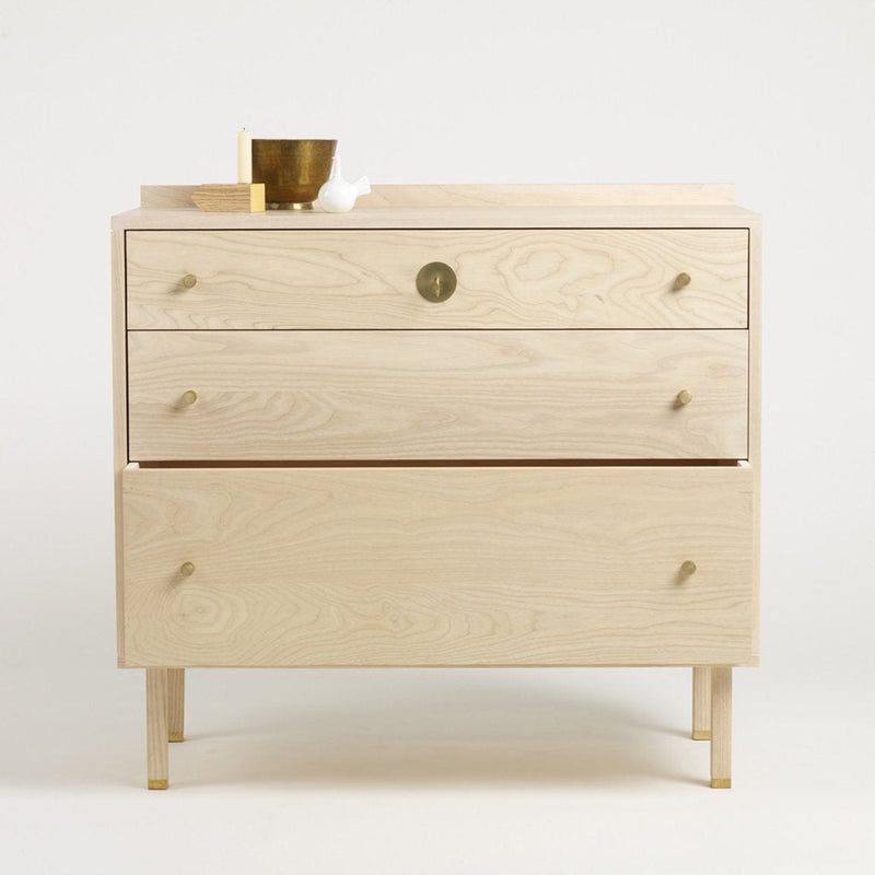 Light wood dresser with three smooth drawers, featuring natural grain and minimalist design. Elegant brass knobs.