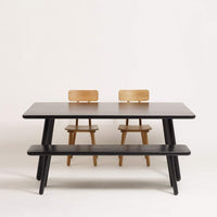 Black and natural wood dining table with minimalist design, featuring a sleek surface and sturdy legs.