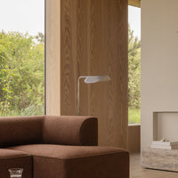Brown plush sofa against a light wood backdrop, featuring soft curves and a minimalist design for a modern look.
