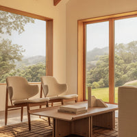 Neutral beige chairs with soft curves, against a warm wood backdrop and a textured brown grid-pattern rug.