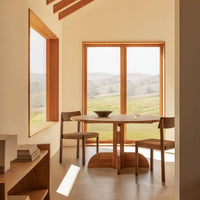 Natural wood tones and soft earth colors complement the minimalistic modern interior with large windows and scenic views.
