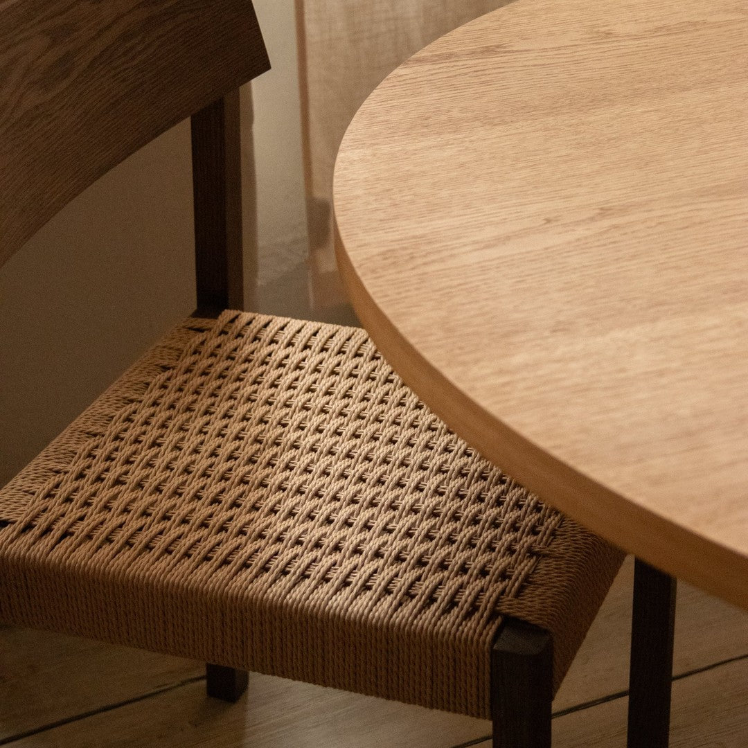 "Natural wood table and woven tan chair, showcasing a minimalist design and earthy tones."