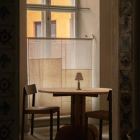 "Neutral-toned fabric curtains with subtle patterns, complementing a warm, natural wood table and chairs."