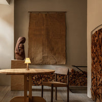 Warm beige wall hanging with textured patterns, complemented by natural wood tones in a cozy interior setting.