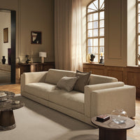 Beige fabric sofa with clean lines, featuring textured cushions. Soft neutral tones complement a modern interior.