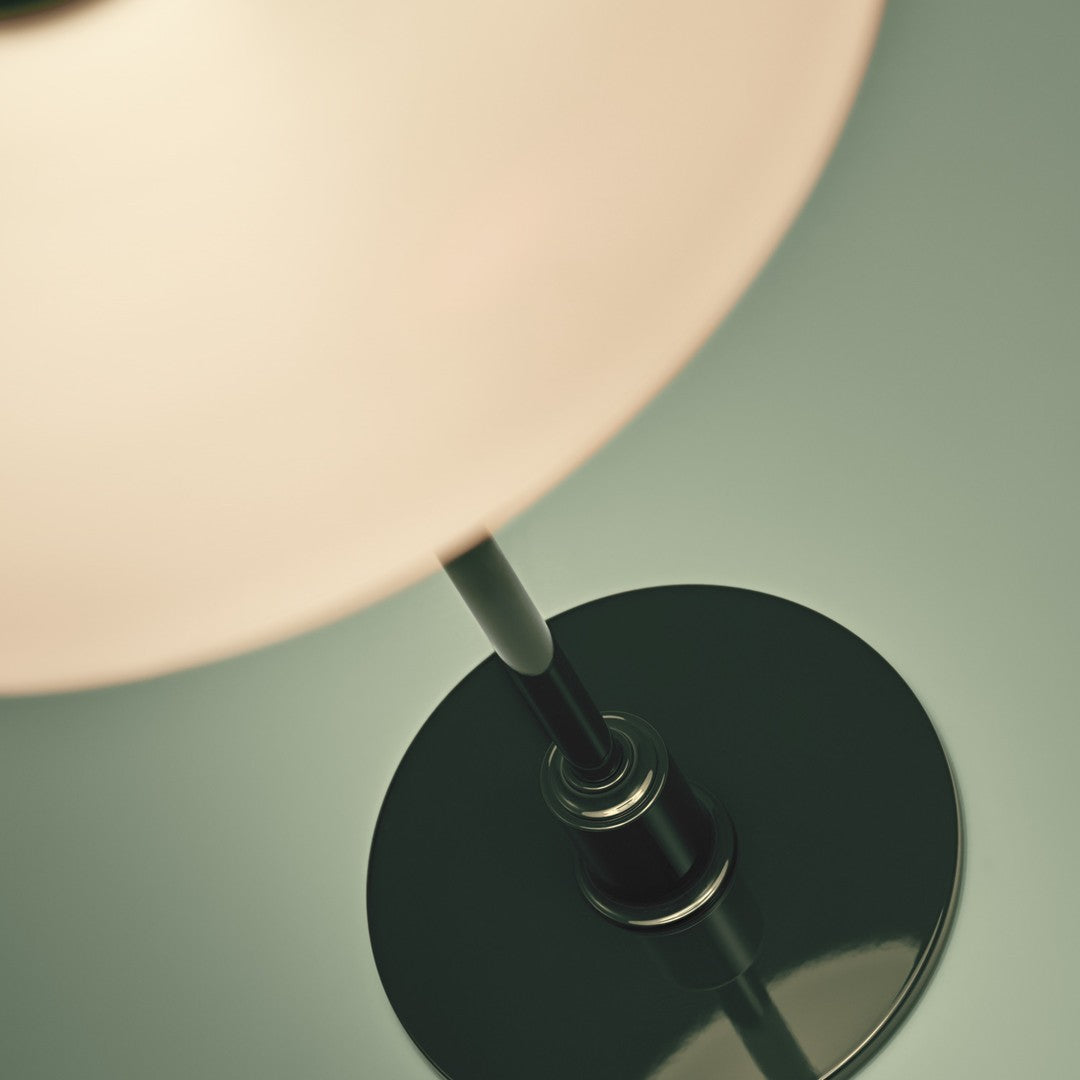 Black lamp base with a sleek, modern design and a soft, glowing white shade against a muted green background.