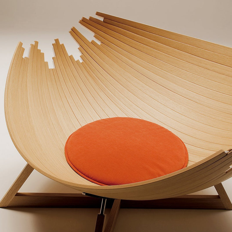 Curved wooden lounge chair featuring a natural finish and vibrant orange cushion for a modern aesthetic.