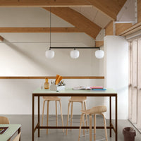 Modern kitchen with natural wood accents, white pendant lights, and a mint green table, featuring sleek, minimalist design.