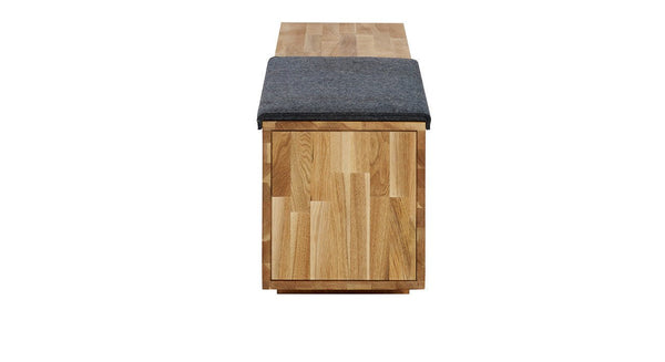 Wooden bench with a natural finish and a dark gray cushion on top. Simple, modern design with a sleek pattern.