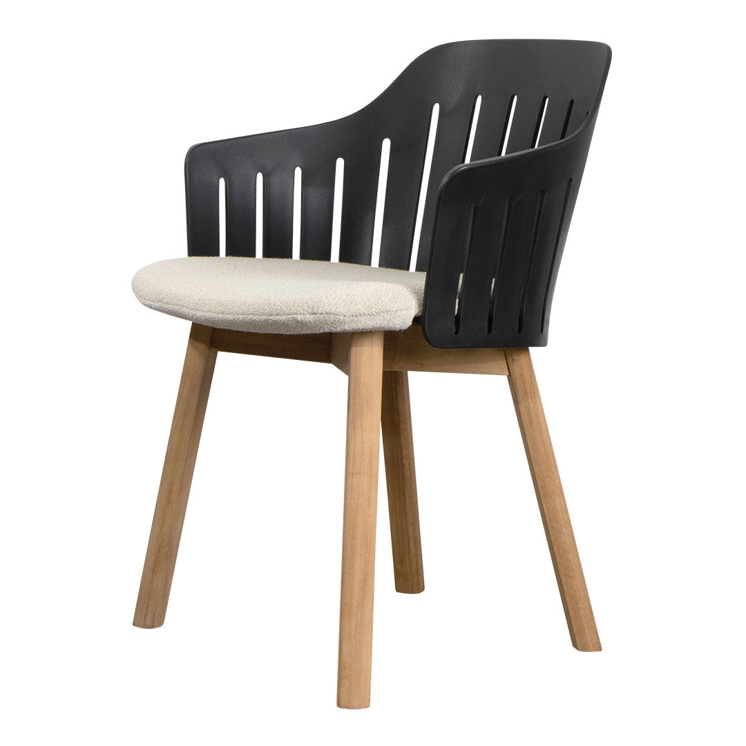 Black slatted chair with a cream cushion and natural wood legs perfect for modern decor.