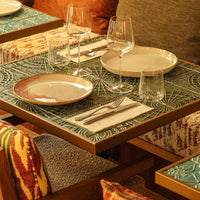 Textured teal table with intricate patterns, surrounded by warm, colorful cushions and elegant tableware.