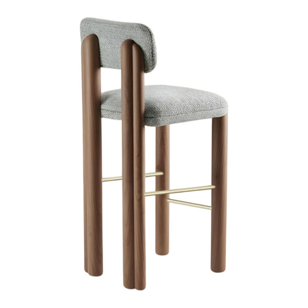 Gray upholstered bar stool with brown wooden legs and a gold metal footrest, featuring a sleek, modern design.