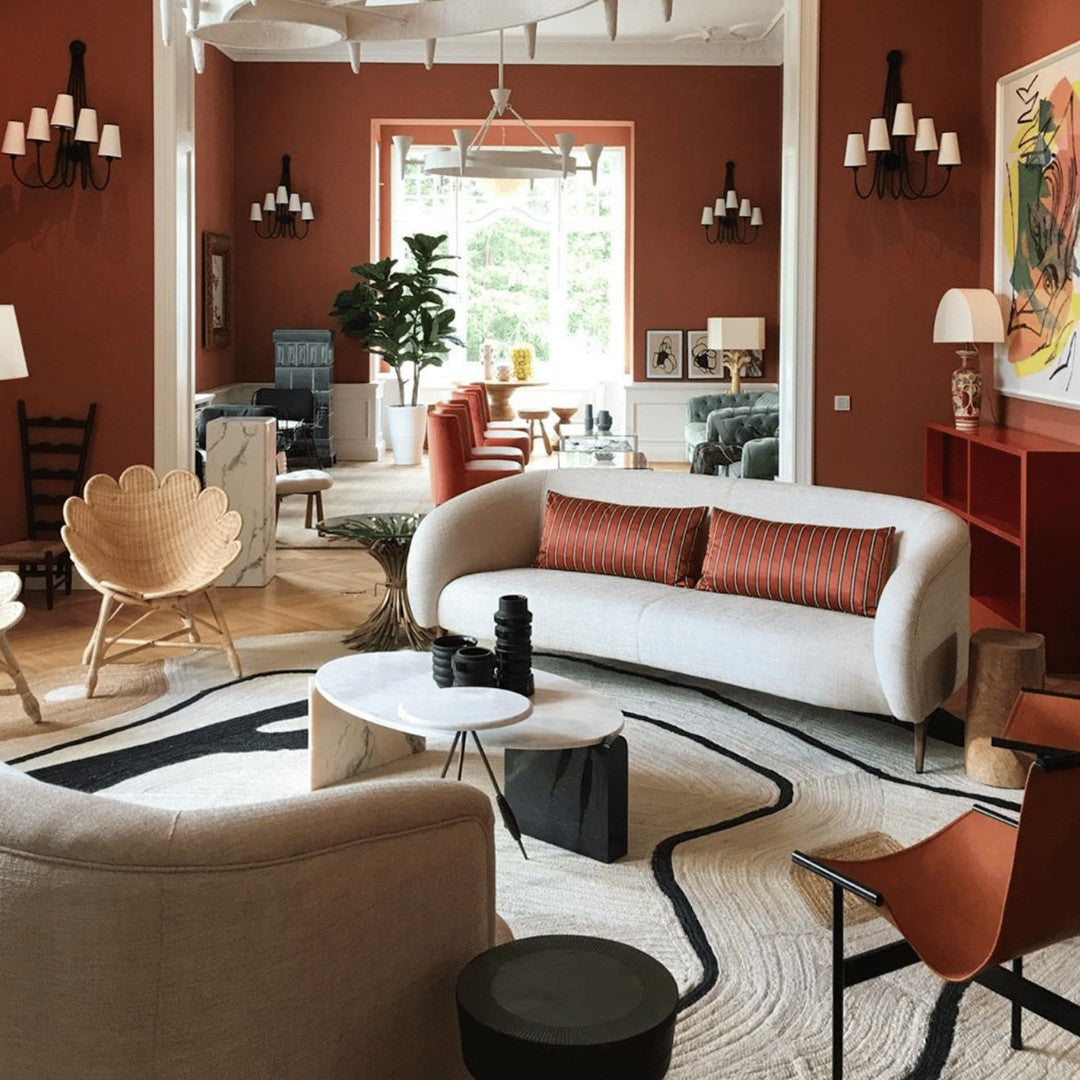 "Modern living room with earthy terracotta walls, cream sofa, bold geometric rug, and rich wood accents."