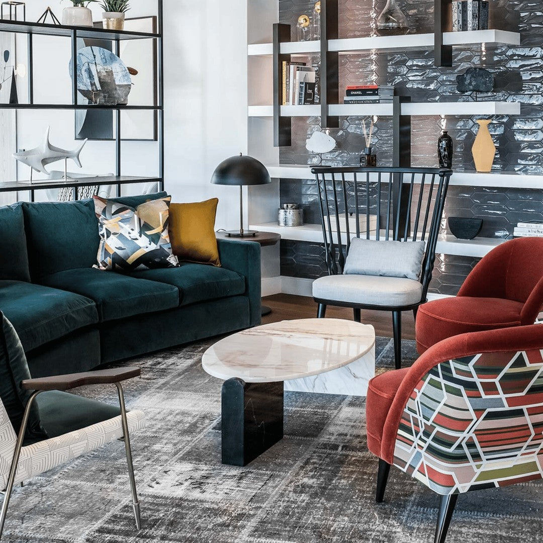 "Plush teal sofa, vibrant red chairs with geometric patterns, and a modern marble coffee table in a stylish living room."
