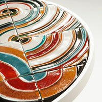 Colorful ceramic plate featuring vibrant swirls of red, blue, orange, and white patterns in a glossy finish.