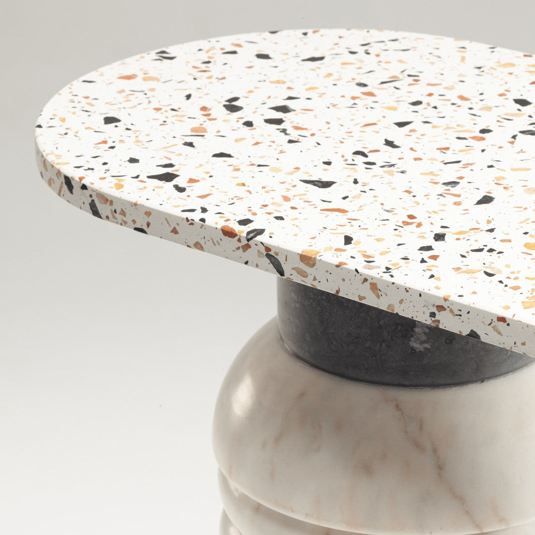 Round tabletop featuring white base with colorful speckles of black, orange, and gray, complemented by a dark pedestal.