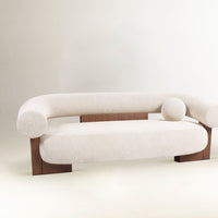 Light beige curved sofa with wooden accents and smooth texture, featuring round cushions for added comfort.
